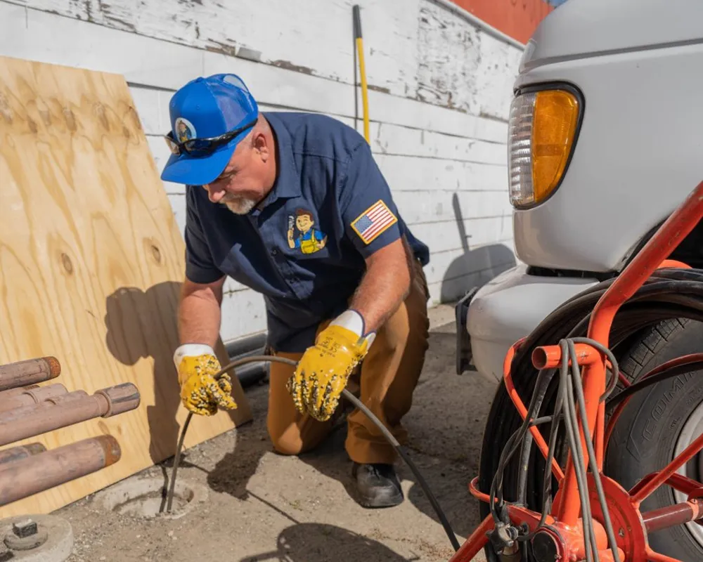 Friendly Services plumber feeding a sewer camera into the line